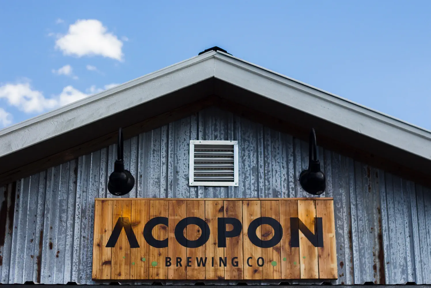 Photo displayed the wordmark for Acpopon Brewing Co., painted onto a woode sign in front of the brewery.